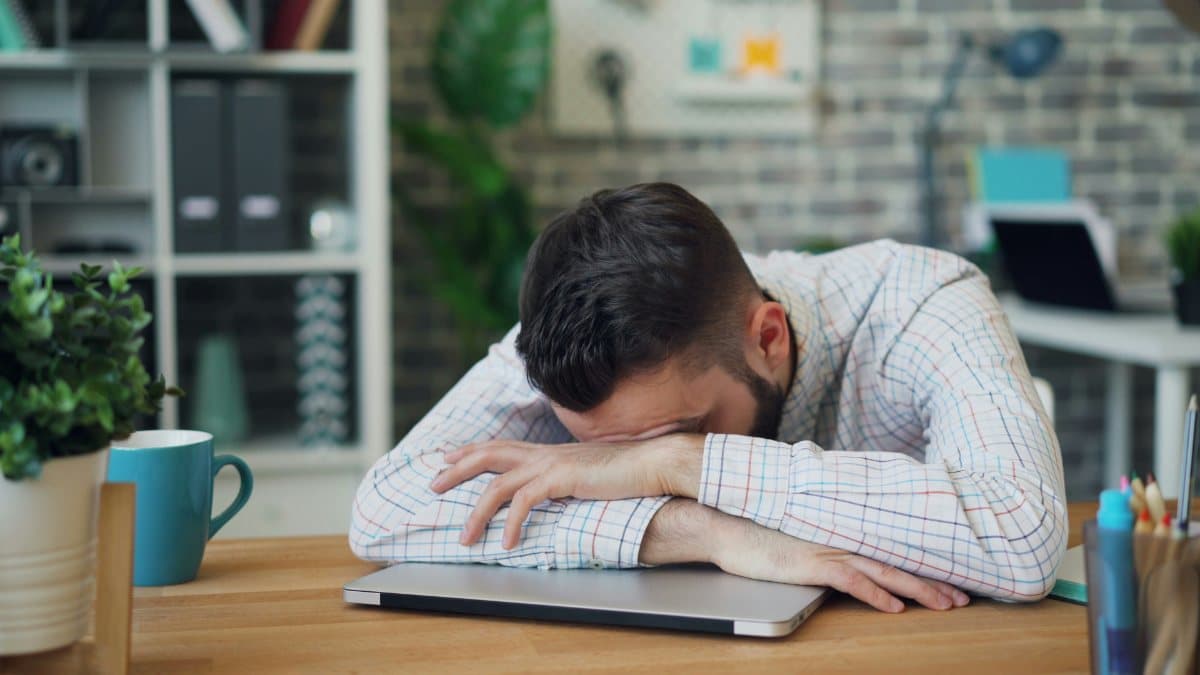 Man asleep with his head on his arms at a desk