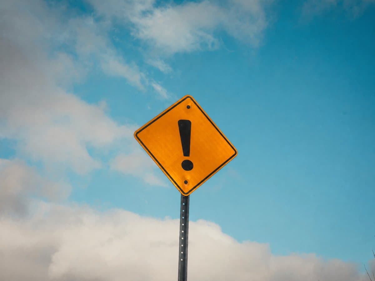 Yellow warning sign with an exclamation mark against a blue sky