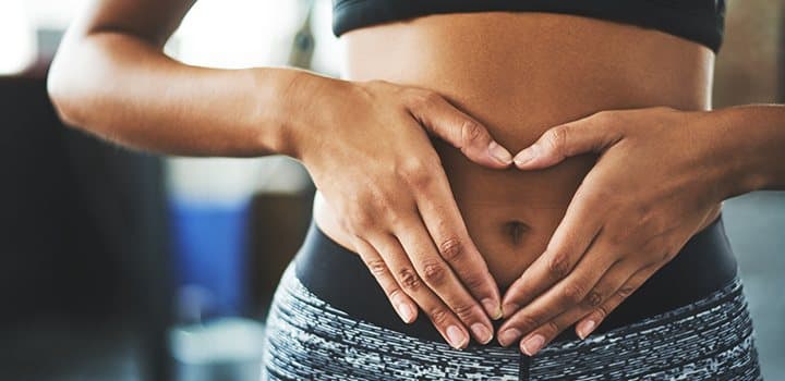 Woman making a heart shape with her hands over her stomach